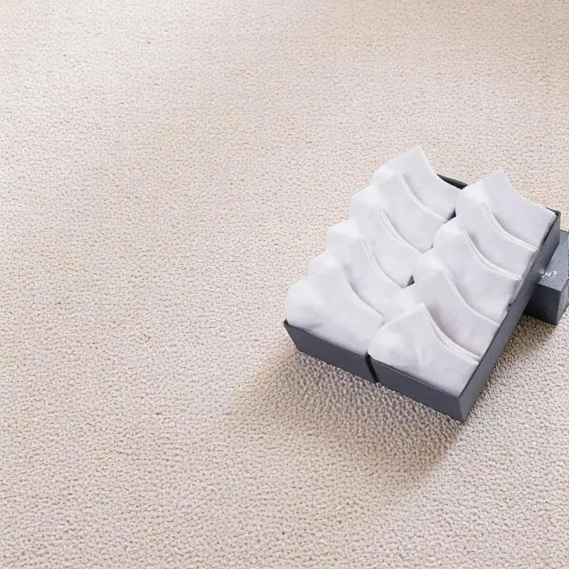 Lot de socquettes invisibles blanches pour homme sur moquette beige.